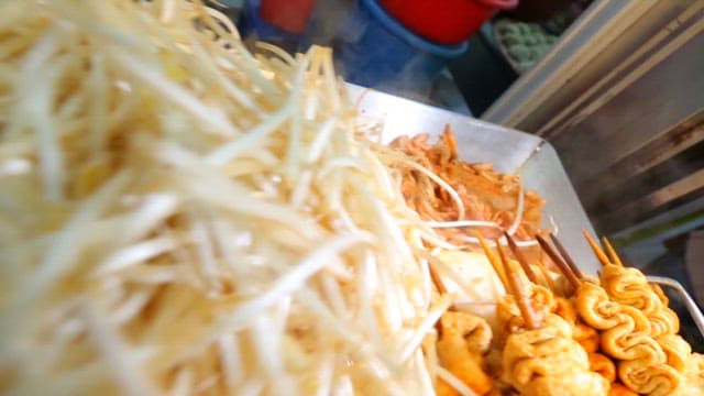 Spicy fish cake skewers and bean sprouts cooked on a hot iron plate