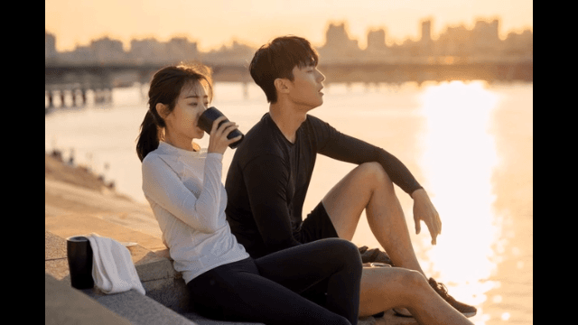 Couple relaxing by river at sunset