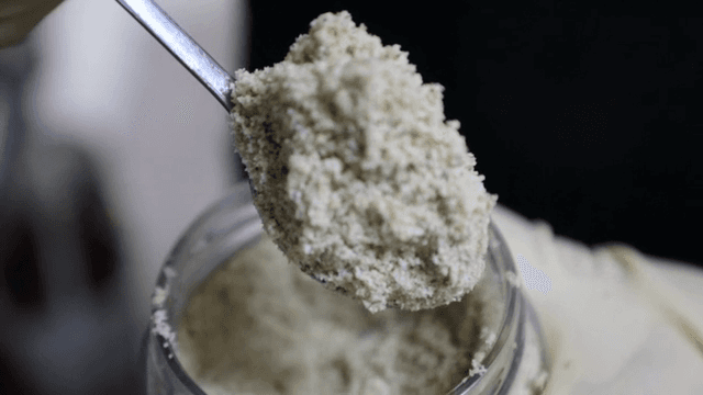 Powder in a jar scooped with a spoon