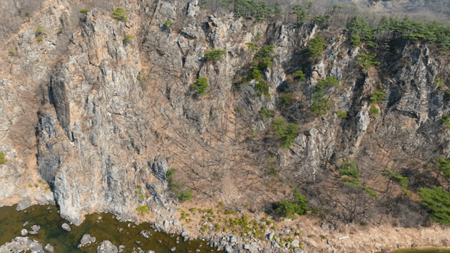 Rocky cliff with sparse trees and river