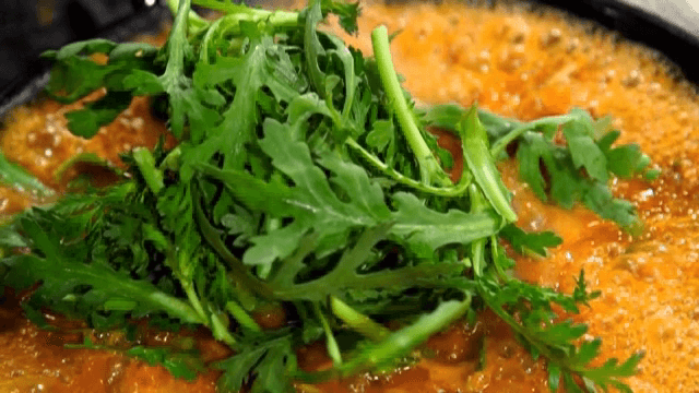 끓고 있는 한국 빨간 찌개에 올리는 쑥갓