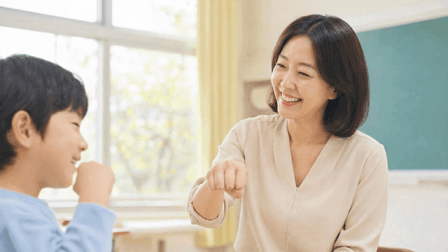Teacher and student exchanging fist bump in classroom