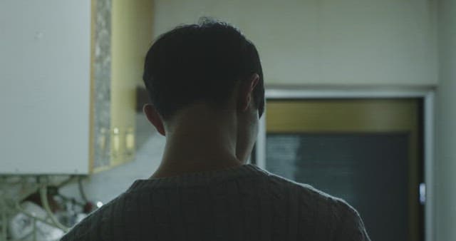 주방에 홀로 서서 핸드폰으로 통화하는 남자