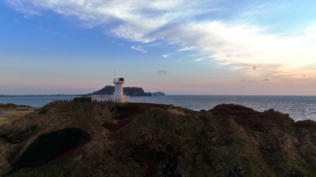 Lighthouse on a coastal hill at sunset