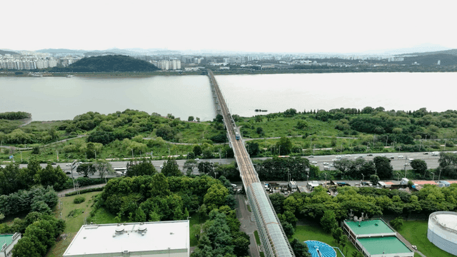 Train crossing bridge over river and city landscape
