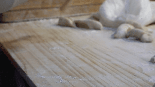 밀가루를 뿌린 표면에서 반죽을 모양내는 손