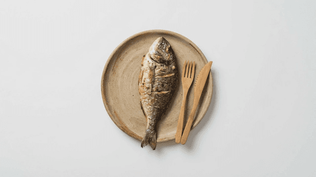Grilled fish on a plate with wooden cutlery