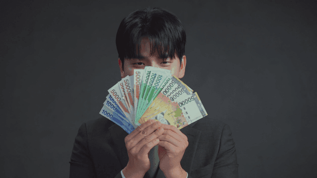 미소를 지으며 한국 지폐를 들고 있는 남자