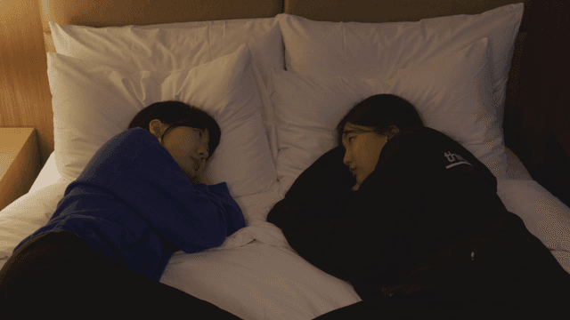 침대 위에서 서로를 바라보며 누워 있는 두 인물
