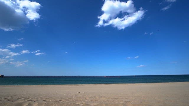 Surfboards arranged on a sandy beach under a clear blue sky