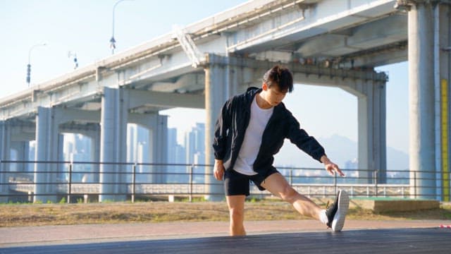 Man stretching under a bridge