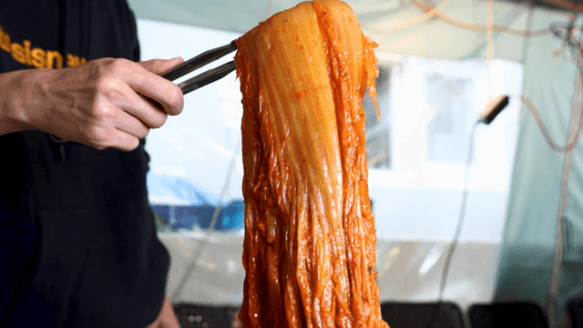 Kimchi stew lifted high with tongs