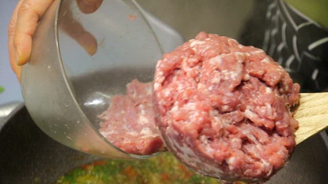 Stir-frying minced meat with vegetables in a frying pan