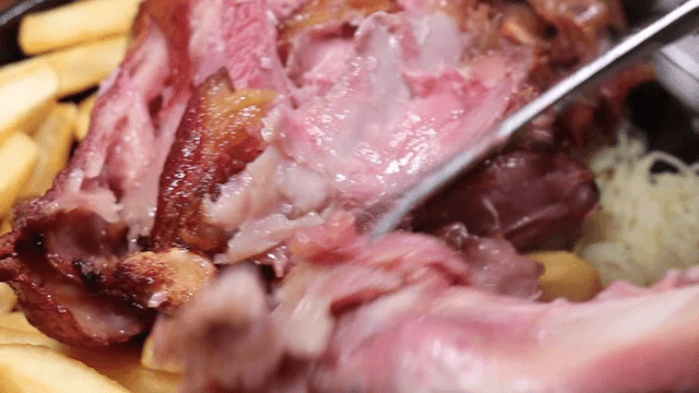Juicy pork being sliced with fries