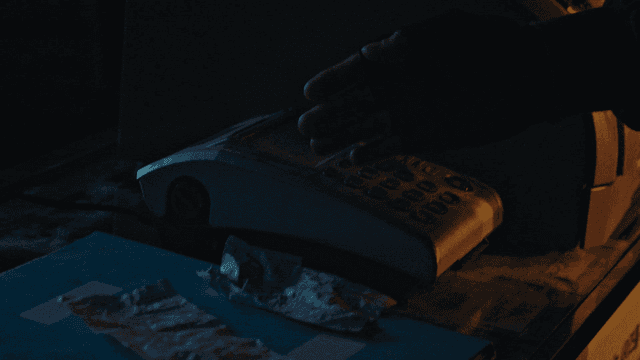 어두운 방에서 먼지 묻은 전화기를 향하는 손