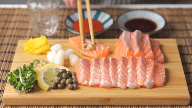 술을 마신 후 연어회에 와사비를 올려 간장에 찍어먹는 모습