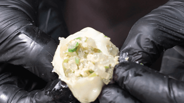 Gloved hands tearing steamed dumplings