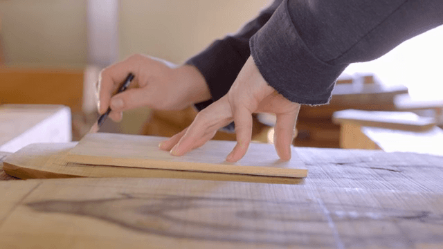 나무 판자를 측정하고 표시하는 손