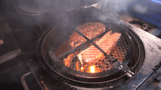 Meat cooked on rotating grill over hot flames