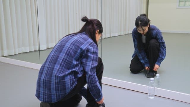 실내에서 신발 끈을 매는 여성