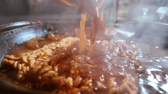 Ramen boiling in spicy seafood stew