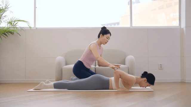 Yoga instructor guiding a student indoors
