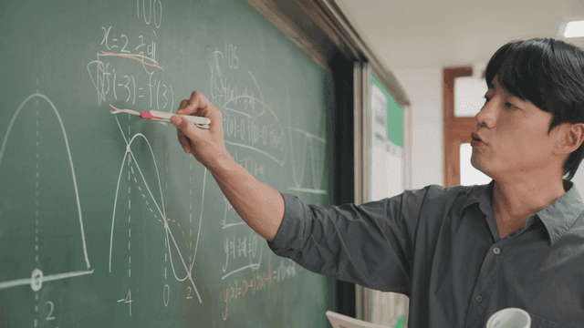 Teacher explaining math on a blackboard
