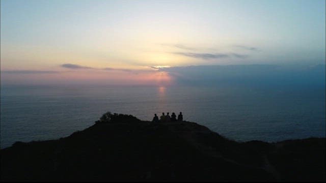 바다를 바라보며 일출을 즐기는 사람들