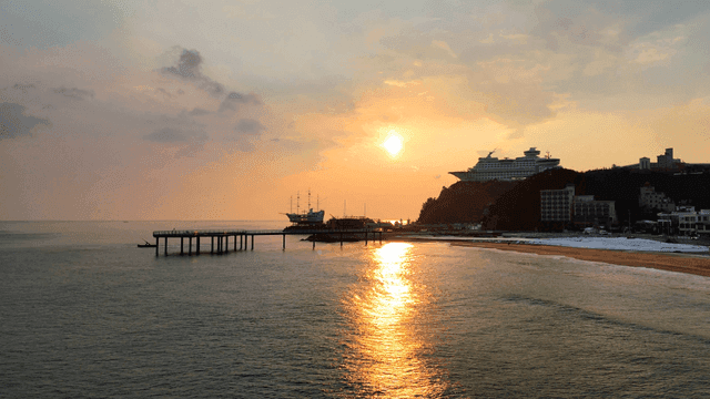 Sunset over a serene beach with a pier