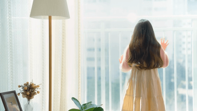 창문 밖을 보며 손을 흔드는 어린 소녀