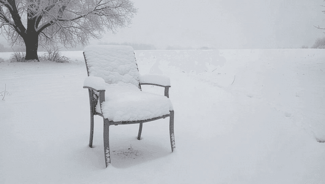 Chair covered in snow in a snowy field