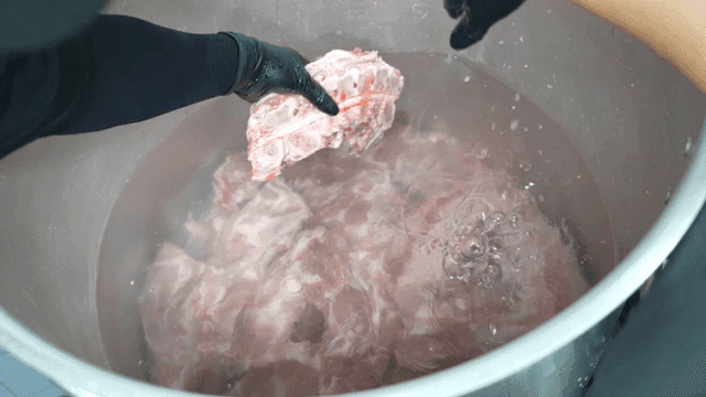 Pork neck bones soaked in large pot of water