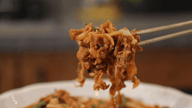 Chopsticks picking up spicy thinly sliced ​​duck bulgogi stir-fried with vegetables