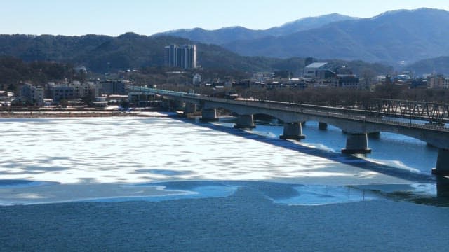 Bridge and Town Landscape over Frozen River in Winter