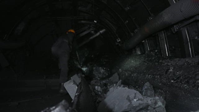 Miner working deep underground in a dark mine tunnel