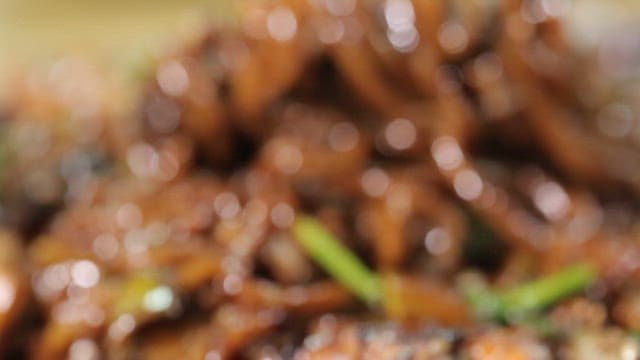 Chopstickful of seafood Jjajang noodles on an iron plate with steaming hot sauce