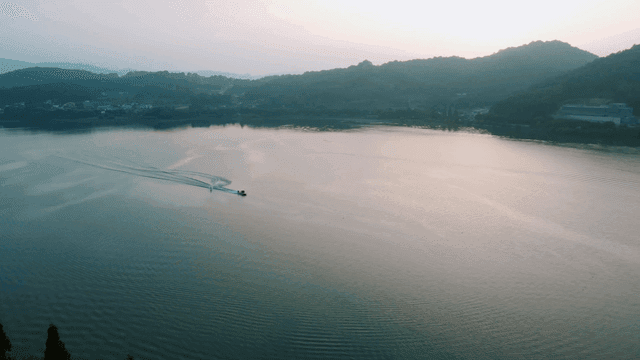 Boats gliding over lake at dawn, water skiing