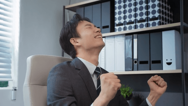 책상에 앉아 환호하는 사업가