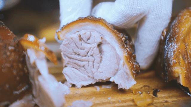 Slicing roasted pig's feet on a wooden board