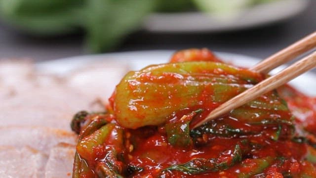 Bok choy kimchi being picked up with chopsticks