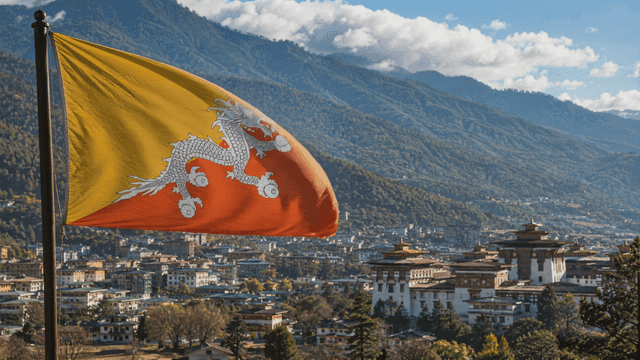 Bhutanese flag fluttering over city with mountains in background