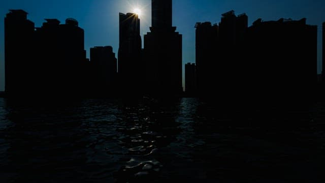 태양을 등진 강변 도시 건물의 실루엣