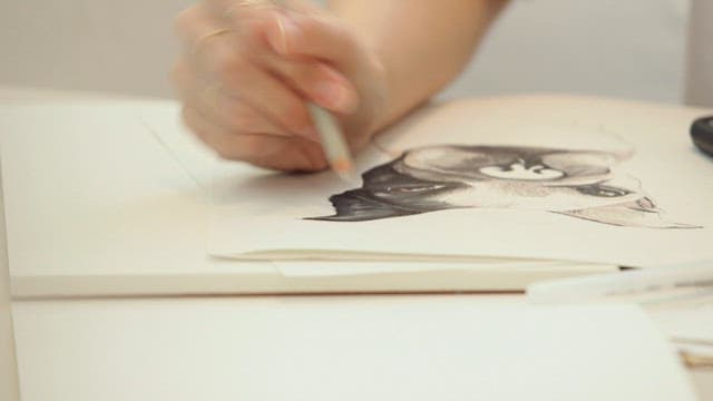실내에서 연필로 종이 위에 강아지를 그리는 모습