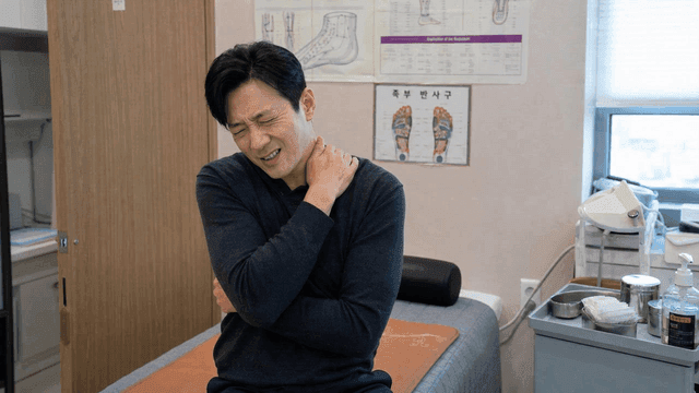 Male patient experiencing neck pain at clinic