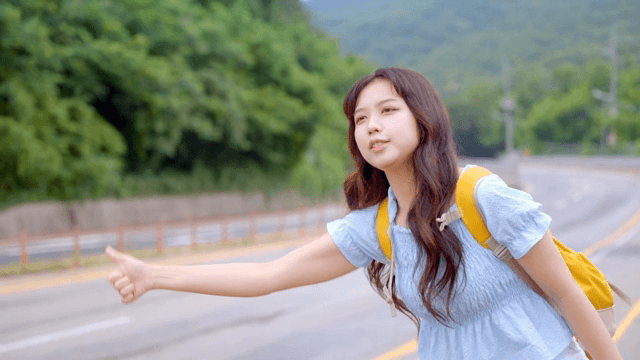 A young woman hitchhiking on a rural road