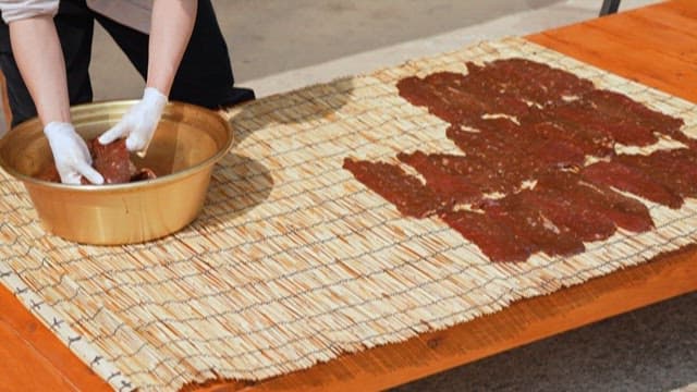 Person drying meat on wooden table