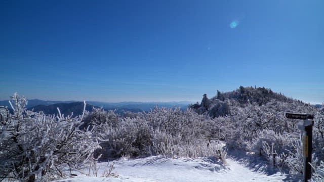 화창한 겨울날 눈 덮인 산꼭대기에서 바라본 전망