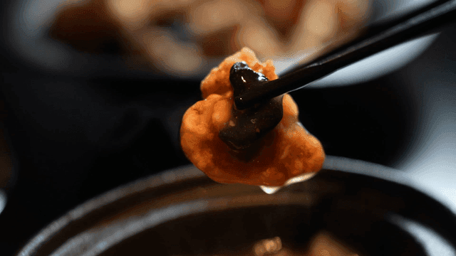 Steaming black garlic tangsuyuk dipped in sauce with chopsticks