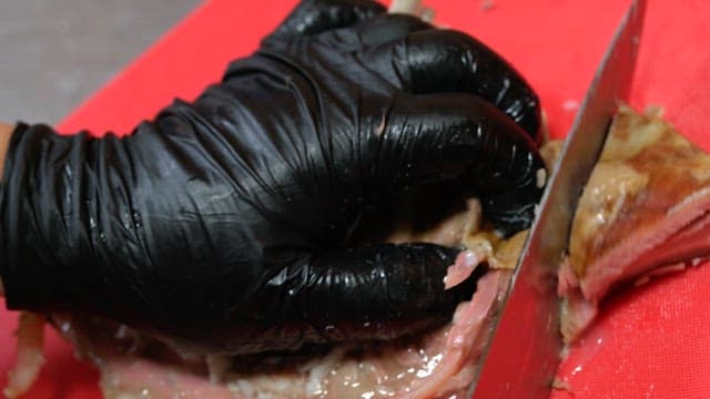 익힌 갈비를 빨간 도마 위에서 정성껏 써는 모습