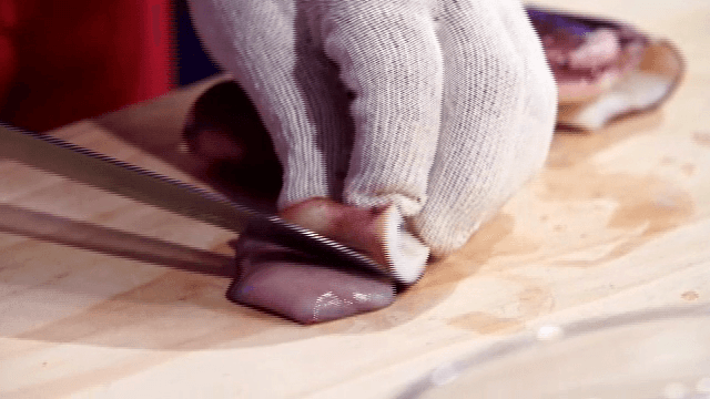 나무 도마 위에서 데친 오징어 자르기